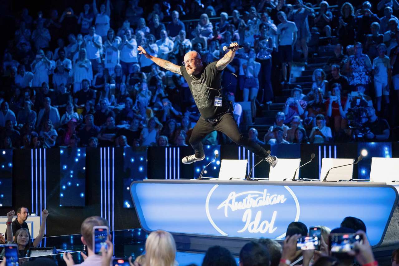 Dave Eastgate leaping across the stage in front of a packed Australian Idol studio audience